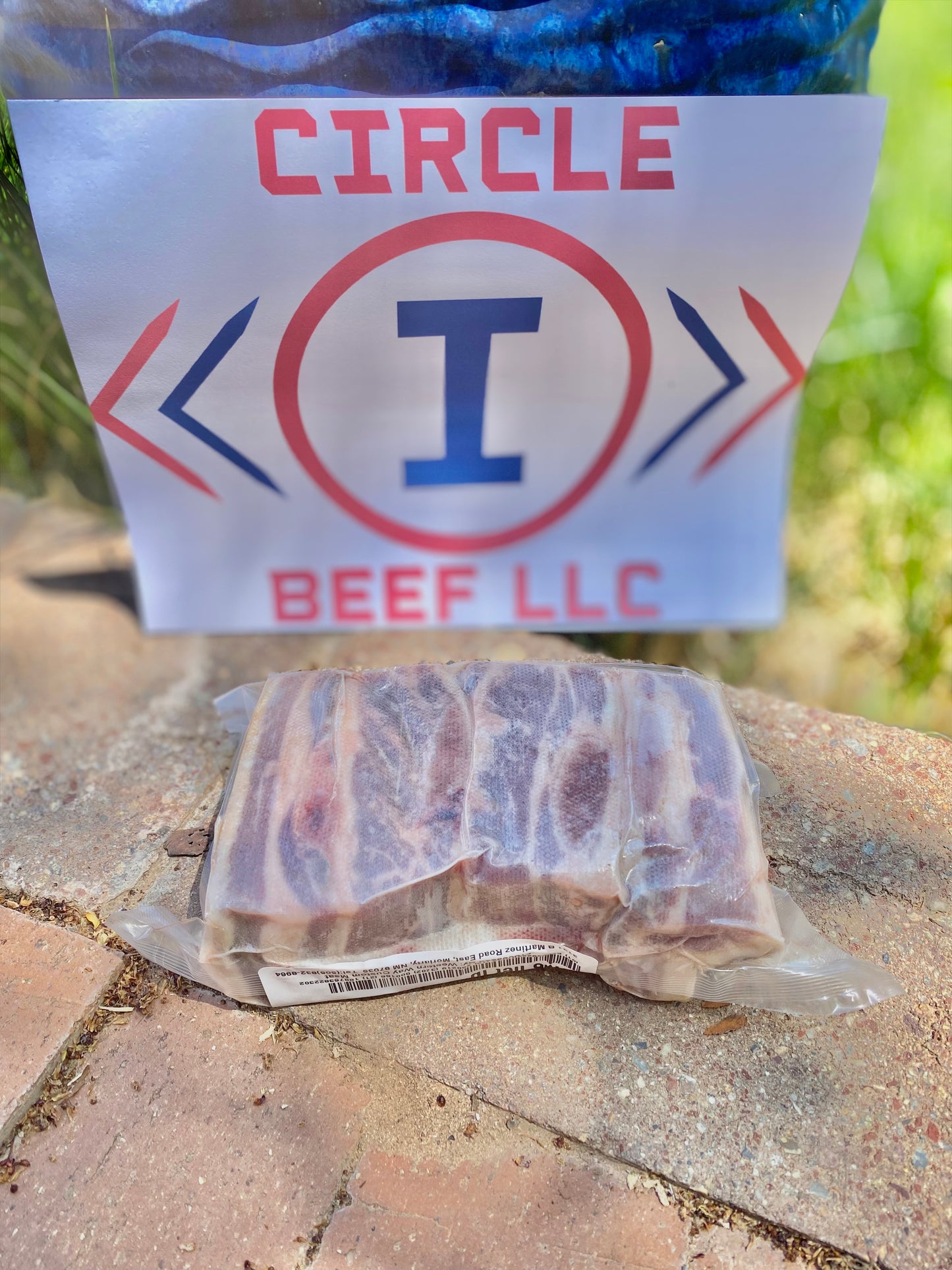 Packaged beef with a 'Circle I Beef LLC' sign on a concrete surface.