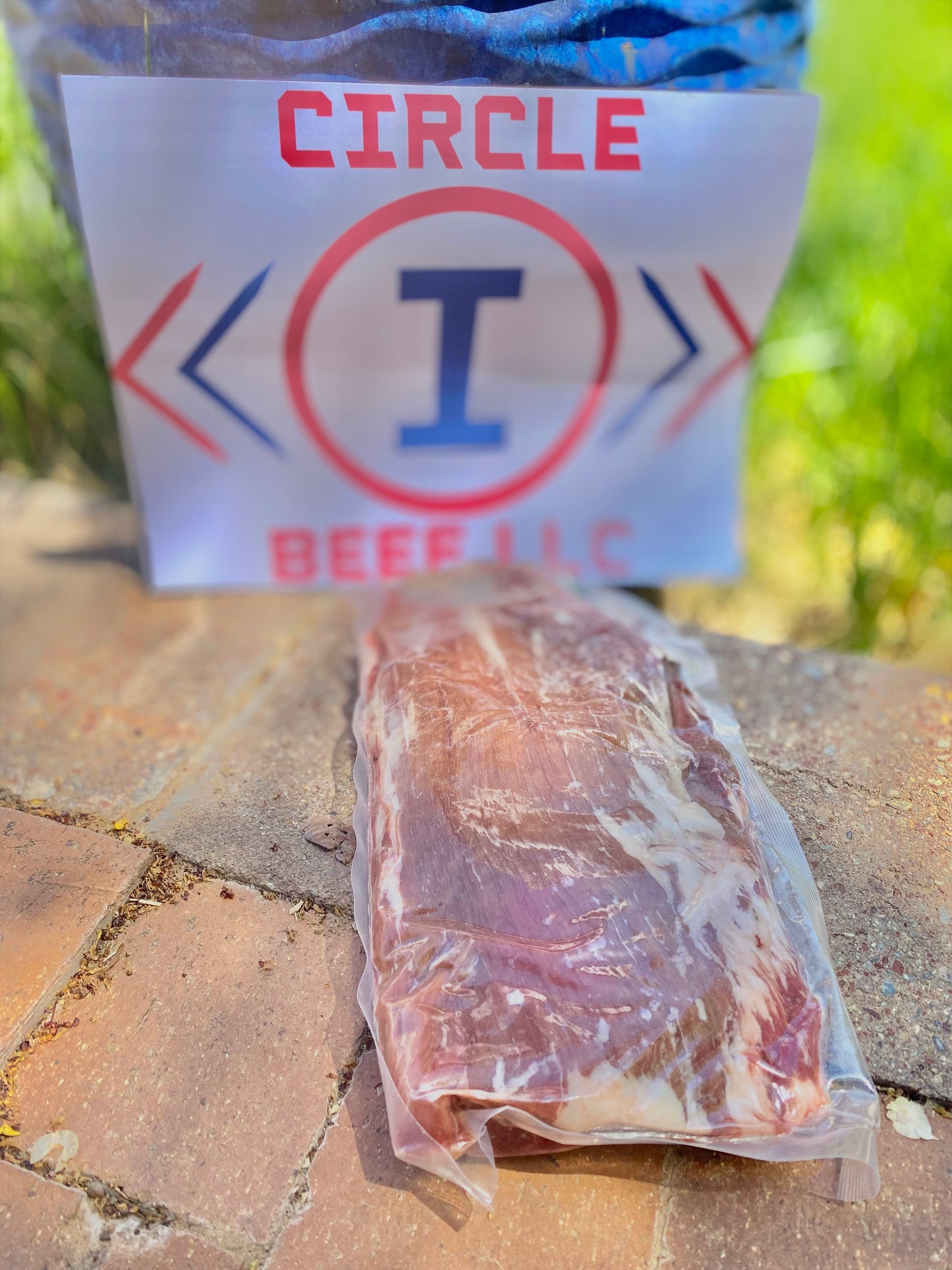 Packaged raw beef on a stone surface with a 'Circle I Beef LLC' sign in the background.